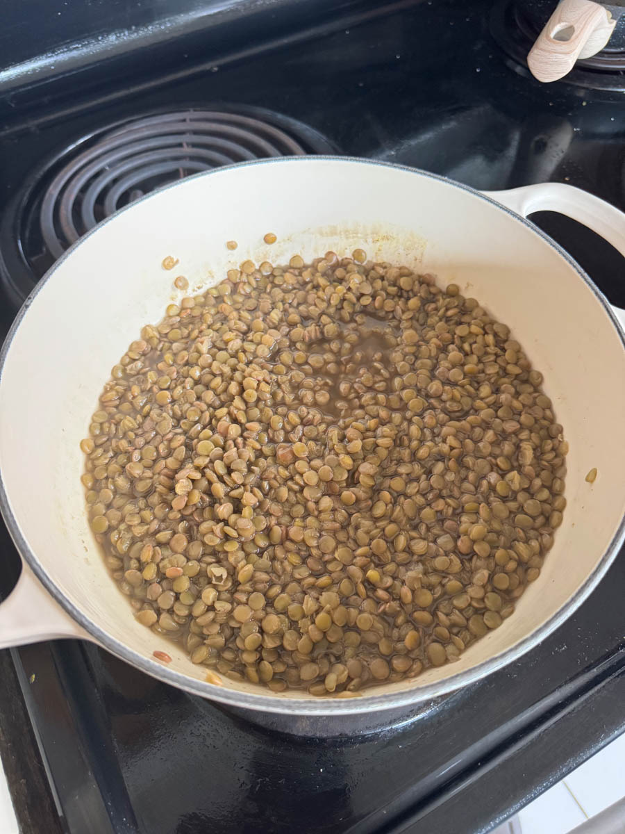 boiling green lentils in white pot