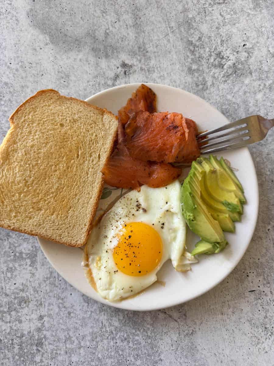 breakfast plate with egg, avocado , toast and smoked fish
