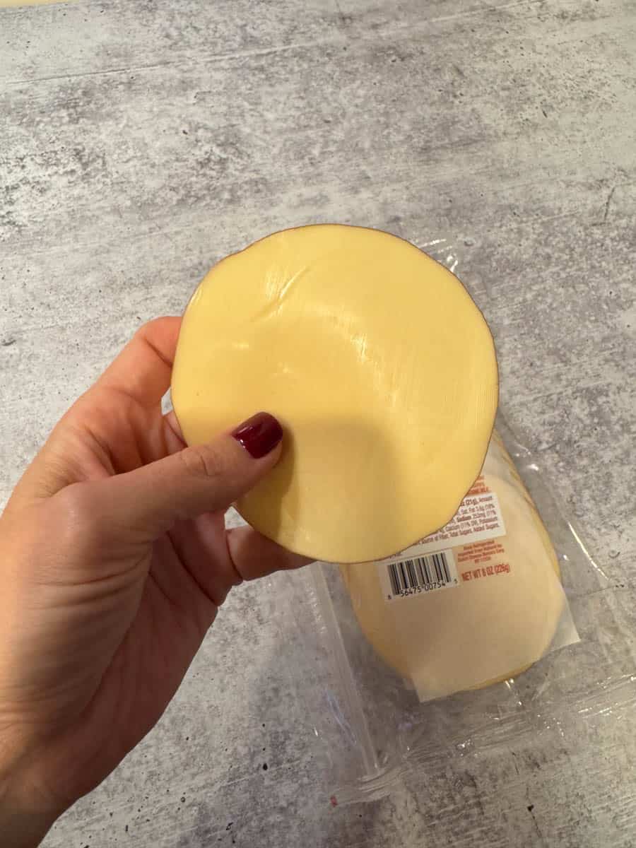 a slice of smoked gouda in hand