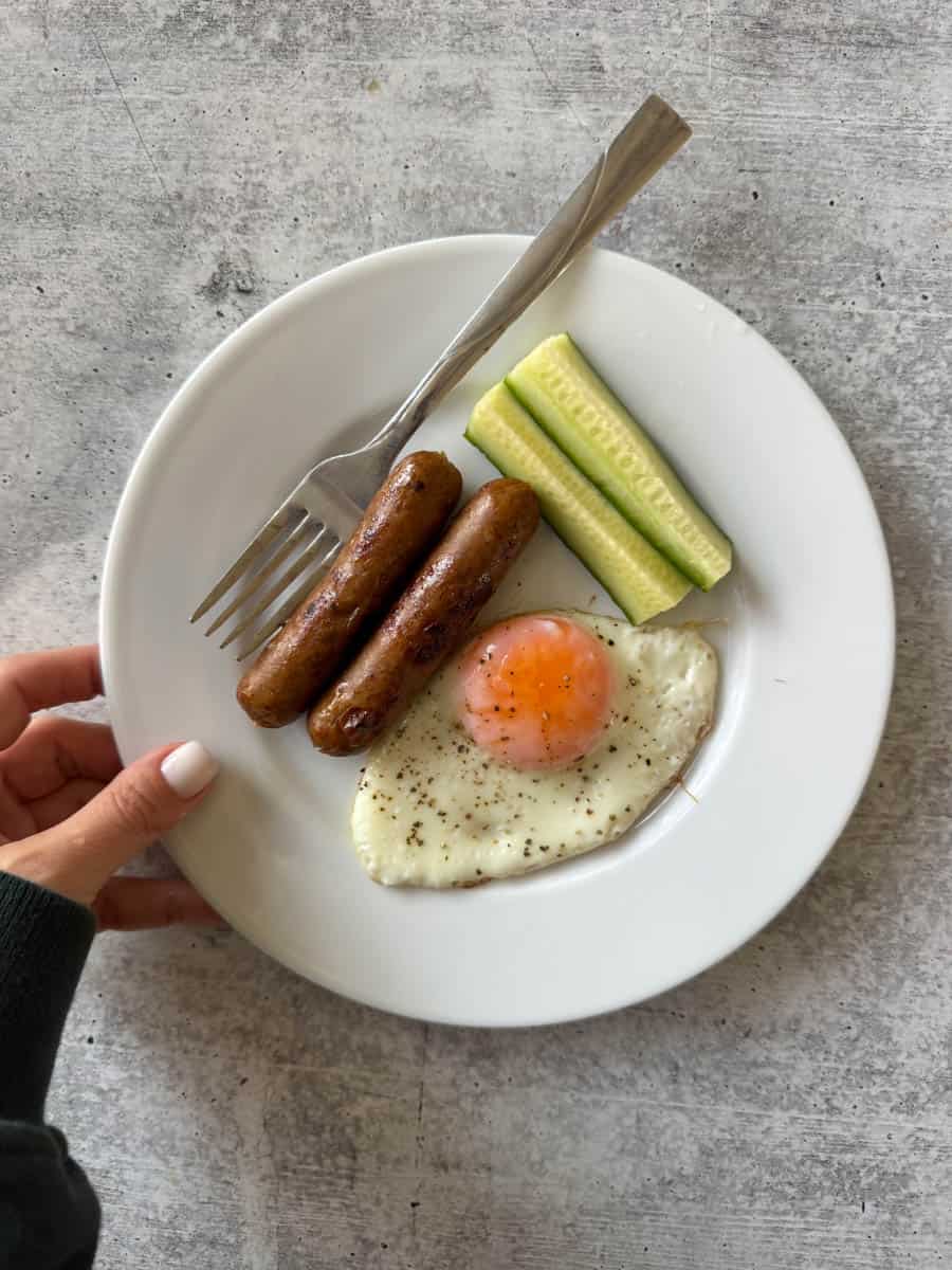 breakfast plate with egg, sausage and cucumbers