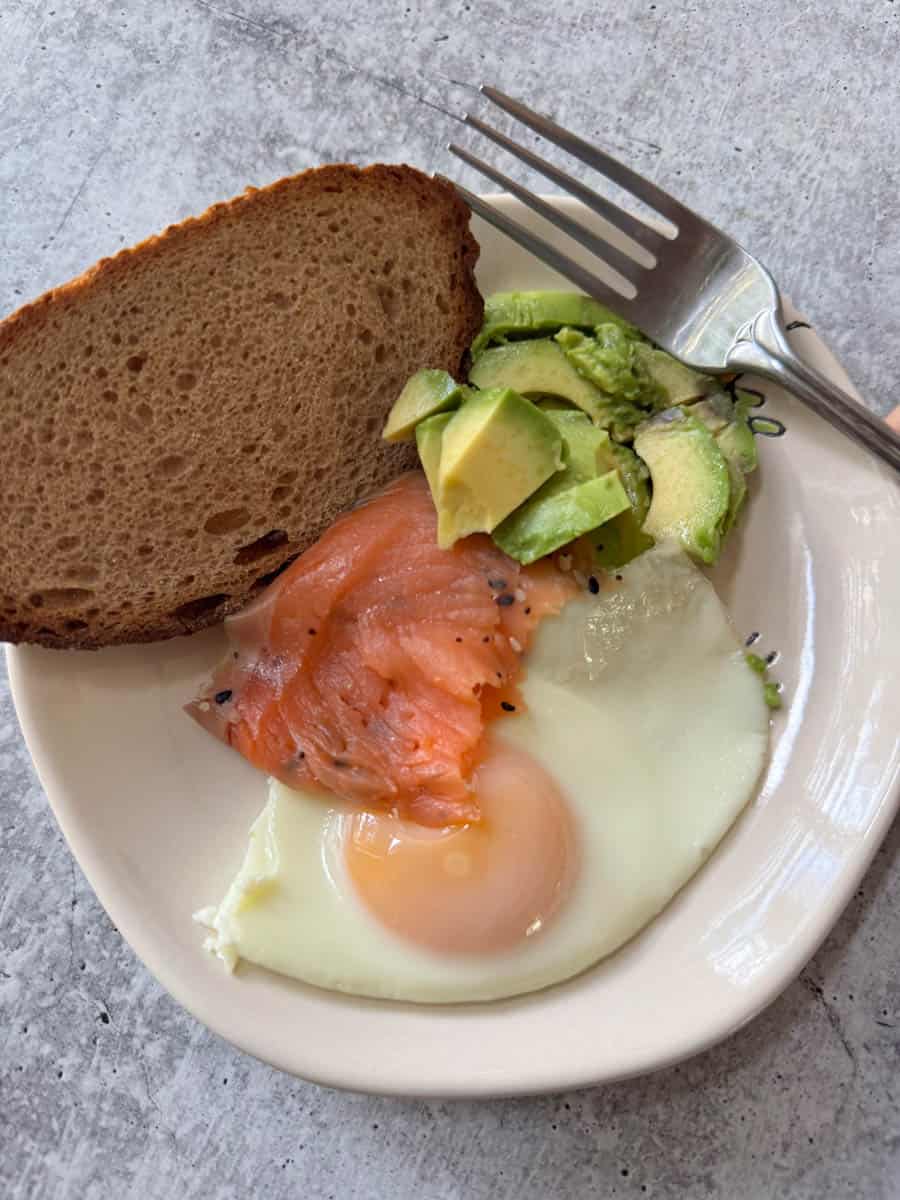 a full plate with eggs, salmon, toast and avocado