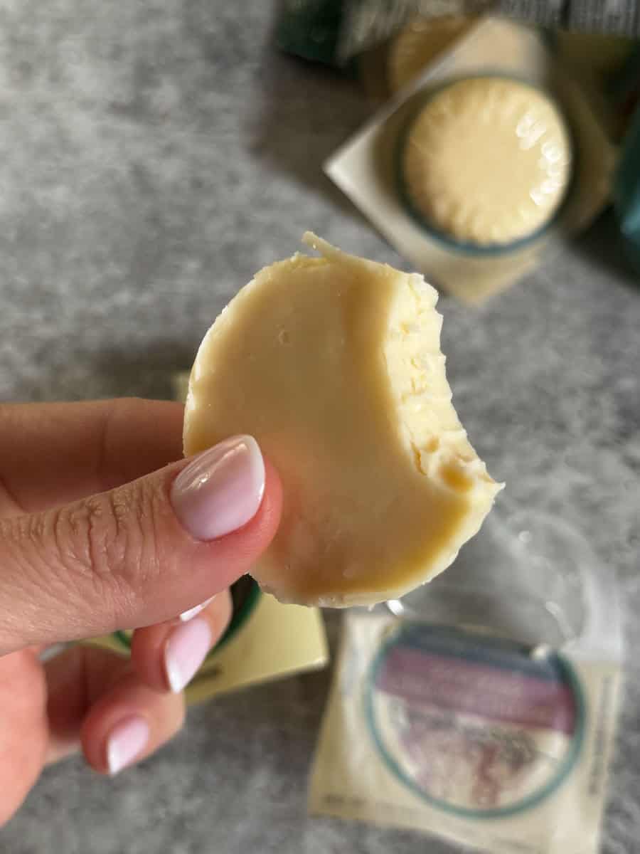 Delicious cheese wedge held by hand, showcasing smooth texture and rich flavor, perfect for cheese l.