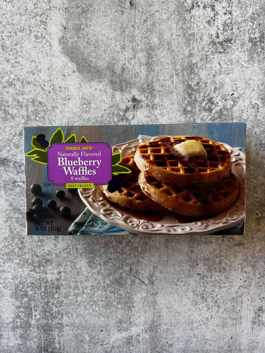 Delicious blueberry waffles topped with butter, served on a decorative plate.