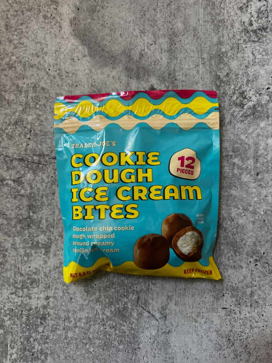 Pack of Trader Eats Cookie Dough Ice Cream Bites with 12 pieces, chocolate chip flavor, on a gray su.