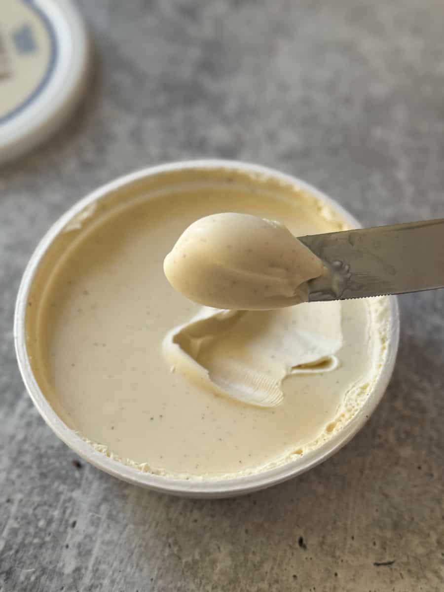 Creamy vanilla ice cream in a cup, with a metal spoon.